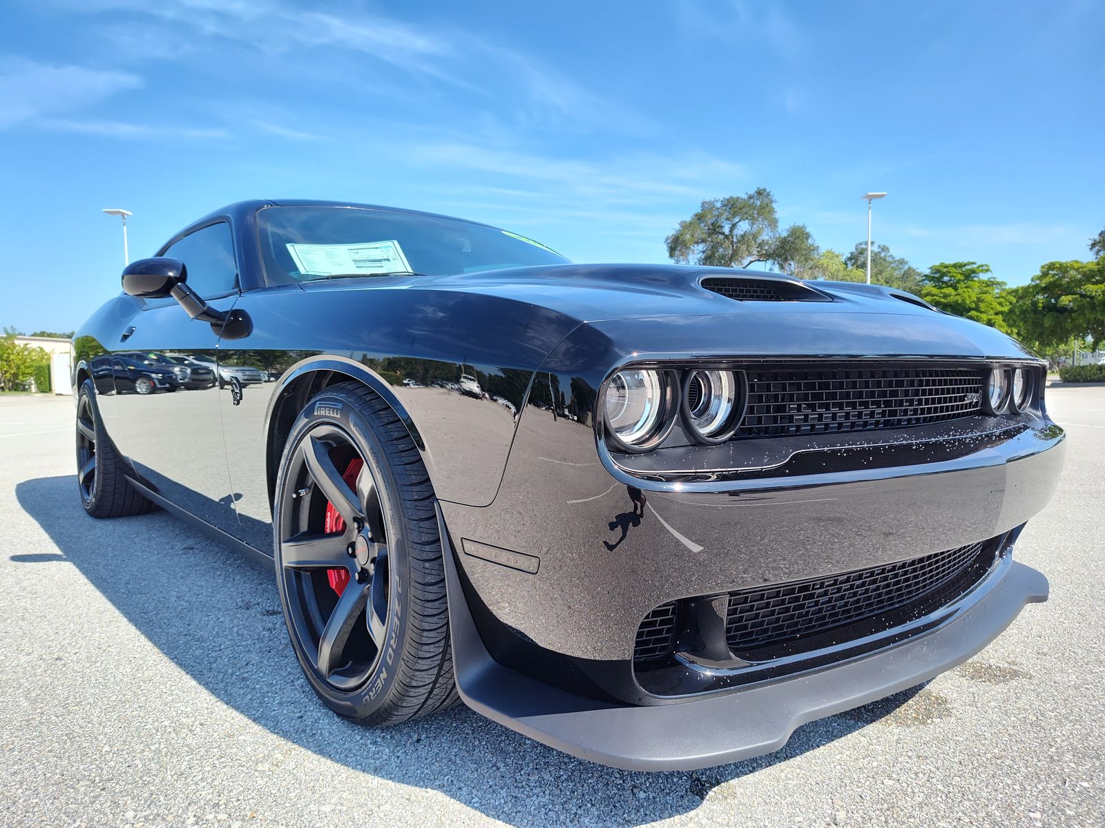 Low front three-quarter of a black Dodge Challenger SRT on a dealership lot.
