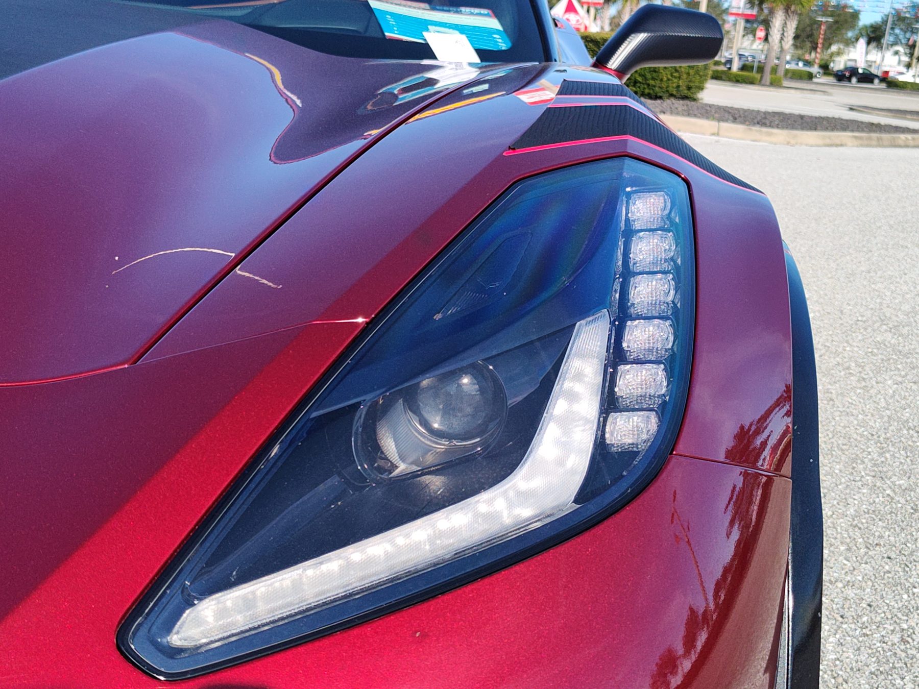 Close-up of a Corvette C7 headlight and fender showing glossy paint finish.